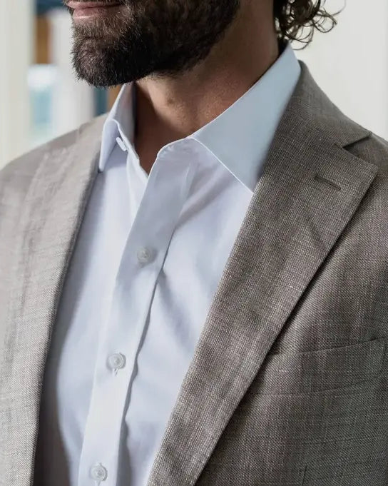 Closeup of a man wearing a white dress shirt and taupe sport jacket