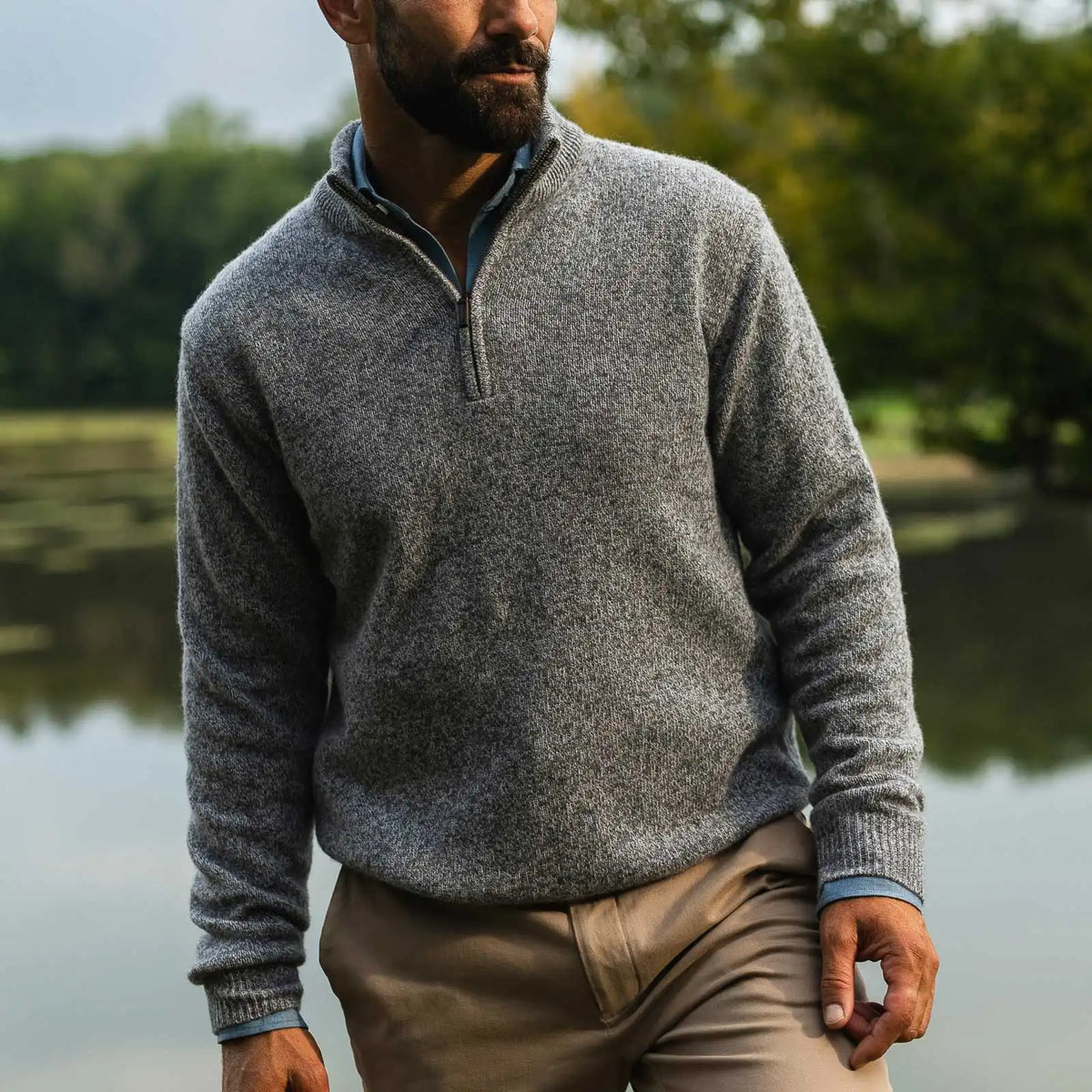 Man standing in an outdoor setting wearing a heathered grey half zip merino wool and cashmere sweater by Ledbury