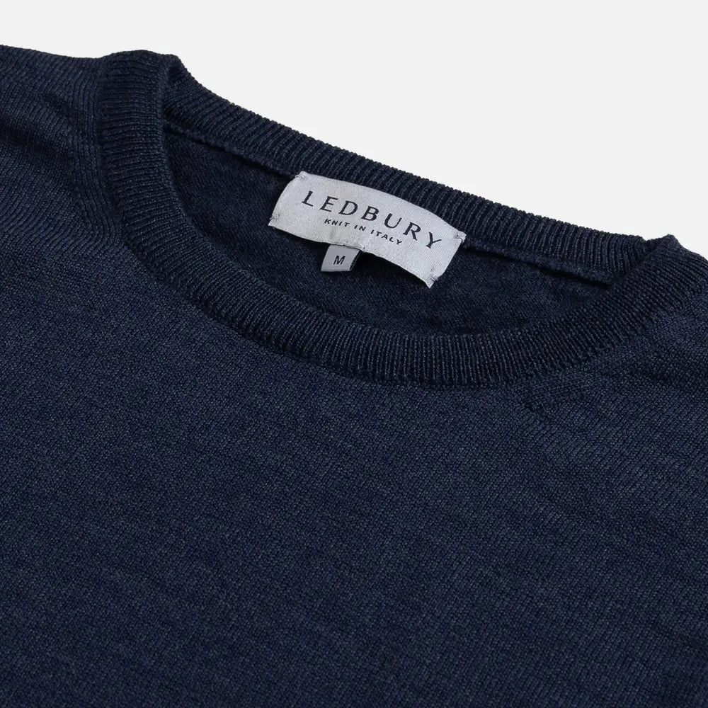 Close-up of a navy blue knit crewneck sweater with a white LEDBURY neck label.