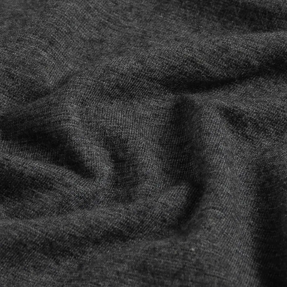 A close-up of dark charcoal gray knit fabric with soft folds and a fine ribbed texture.