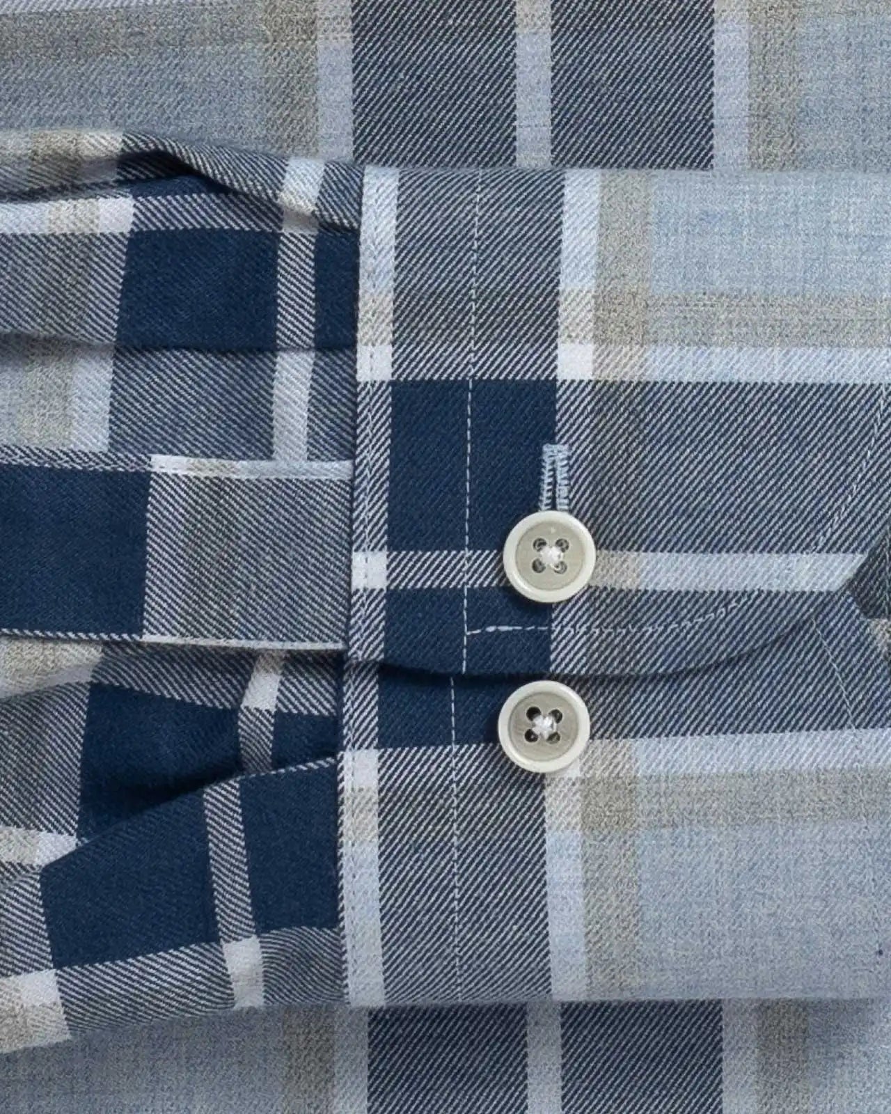 Close-up of the sleeve of a plaid shirt with buttons on a checkered pattern