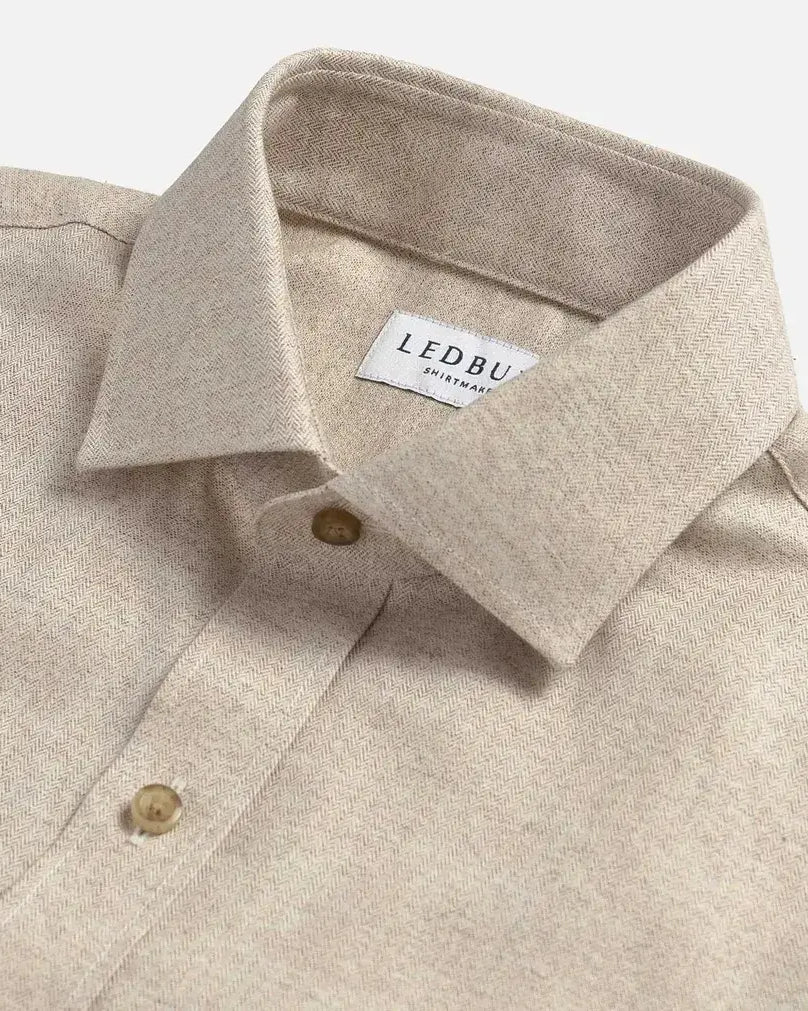 Close-up of an oatmeal colored shirt with a collar and button details