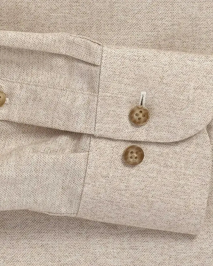 Close-up of a beige textured herringbone shirt with buttons