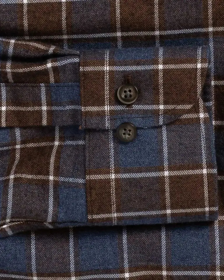 Close-up of a plaid buttoned cuff on a blue and brown flannel-style shirt, showing the fabric texture and dark buttons.