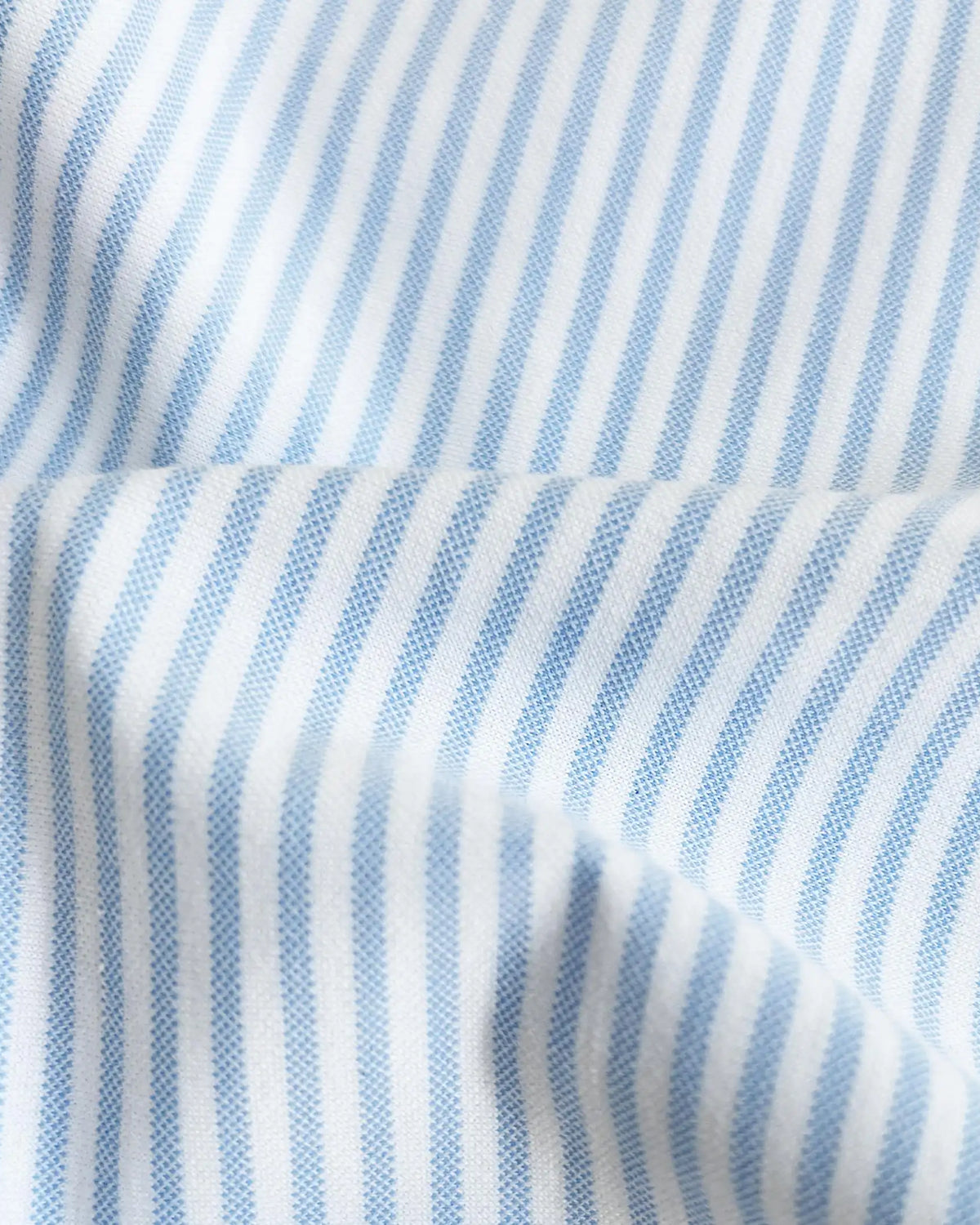 A close-up of light blue and white vertically striped fabric with a soft draped fold.