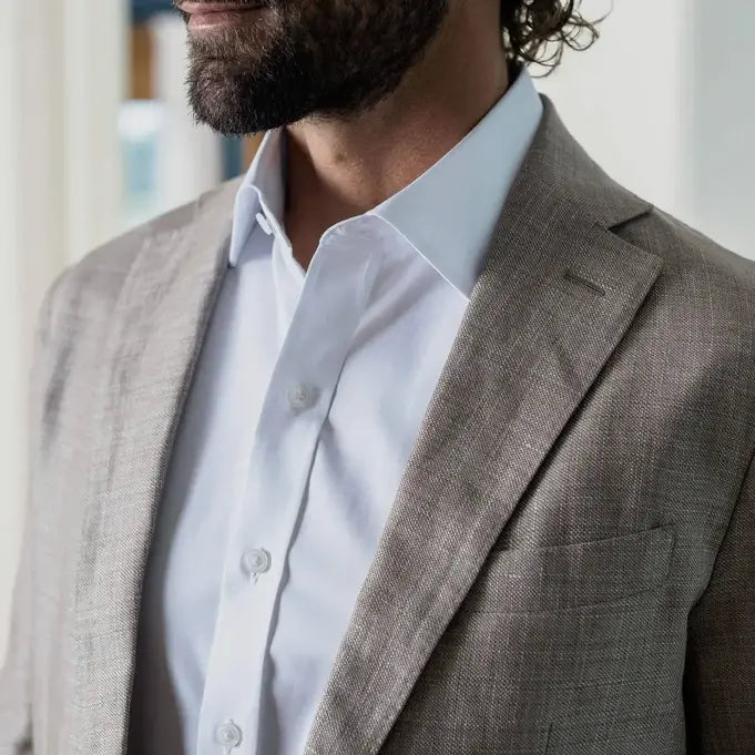 Closeup of a man wearing a white dress shirt and taupe sport jacket