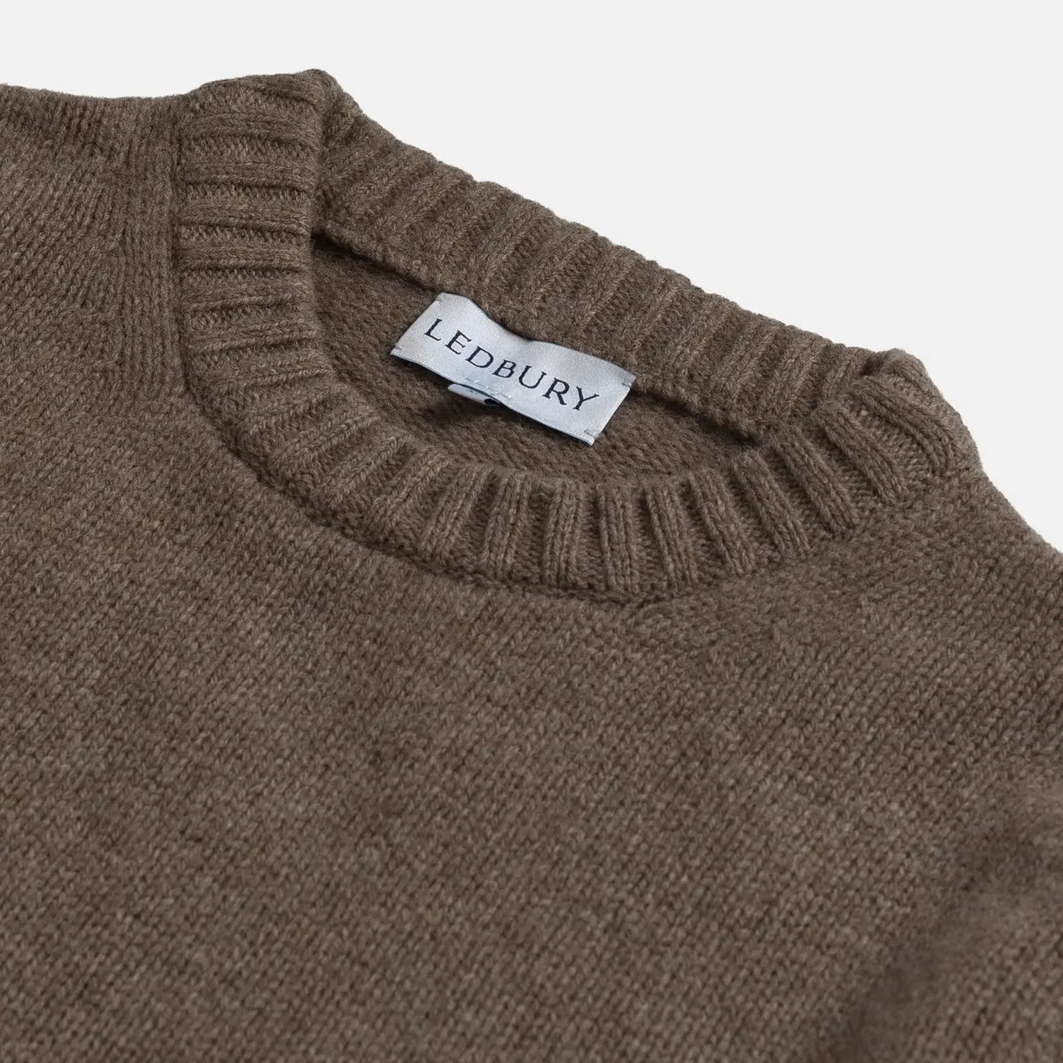 Close-up of a ribbed knit sweater neck with a white LEDBURY brand label visible inside the collar, on a light gray background.