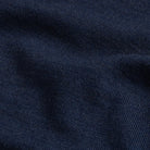 A close-up of dark navy blue ribbed knit fabric with soft folds and a fine textured weave.