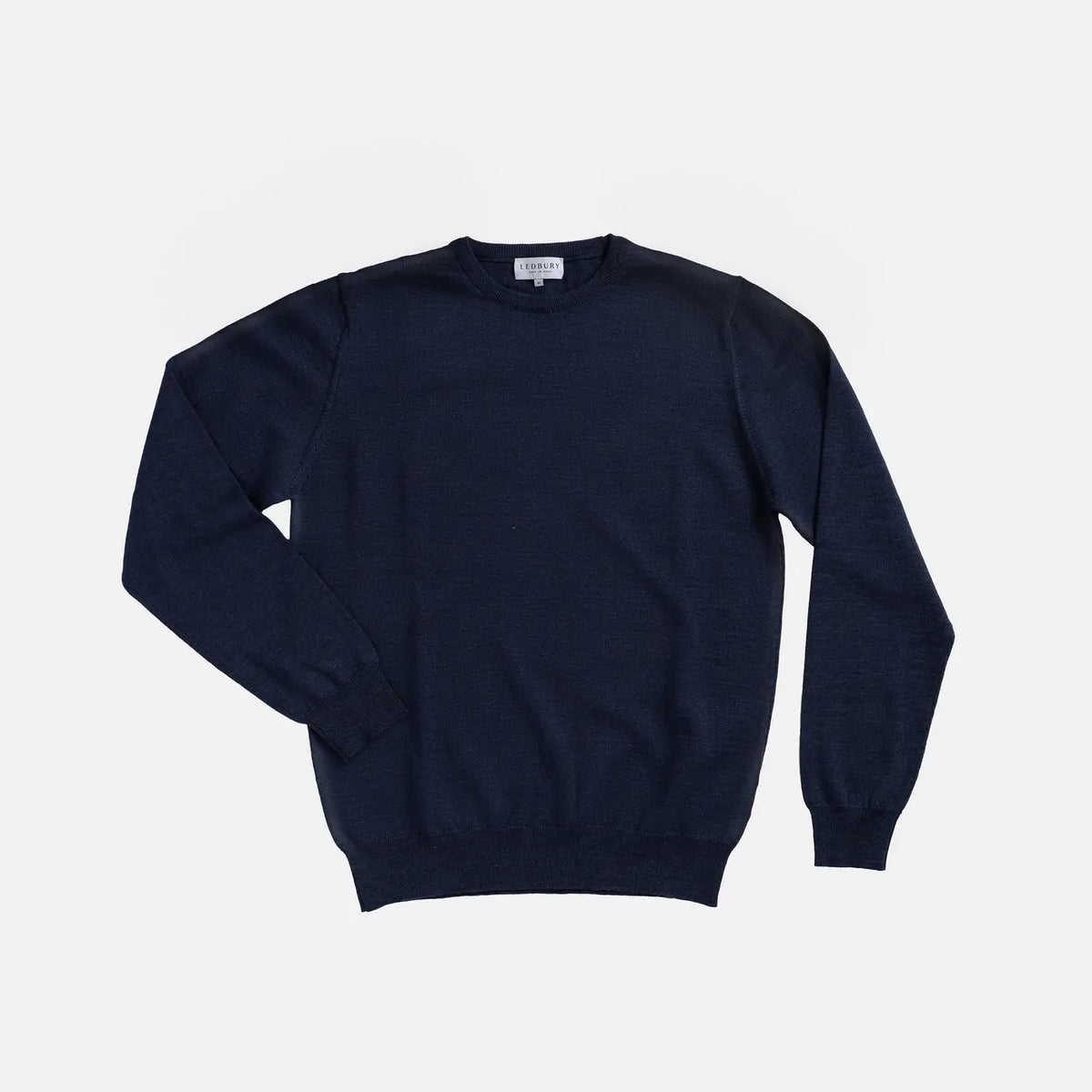 A dark navy blue crewneck sweater laid flat against a light gray background.