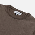 Close-up of a ribbed crewneck sweater in a warm taupe-brown color, showing the white LEDBURY neck label.
