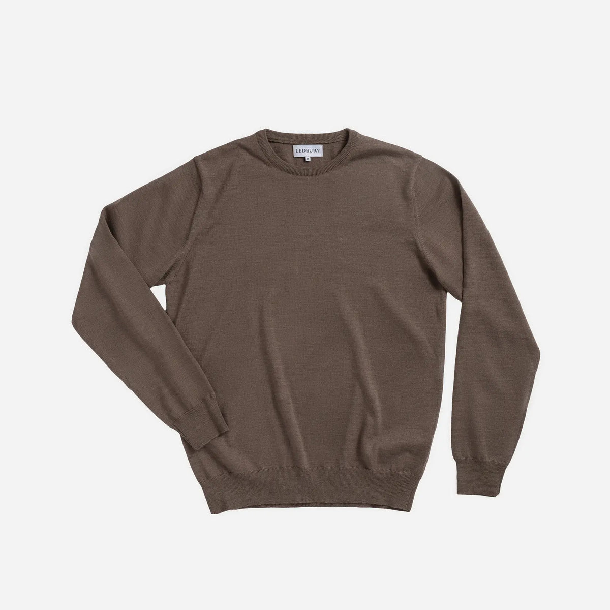 A brown crewneck knit sweater with long sleeves, laid flat against a light gray background.