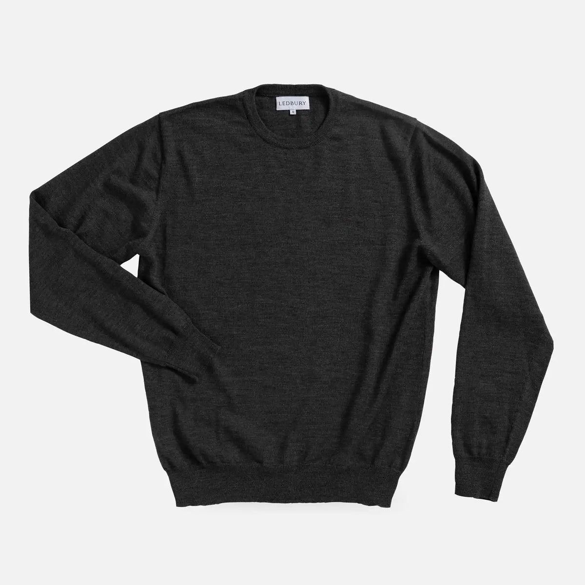 A dark charcoal gray long-sleeve crewneck sweater laid flat against a light gray background.