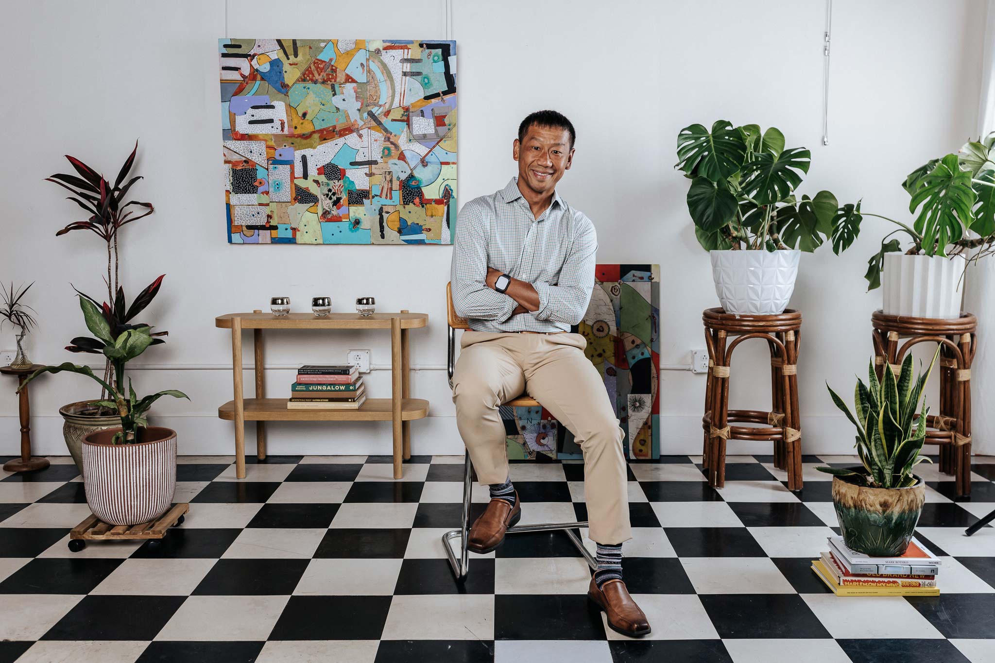 Man sitting on a stool in a room with plants and colorful wall art
