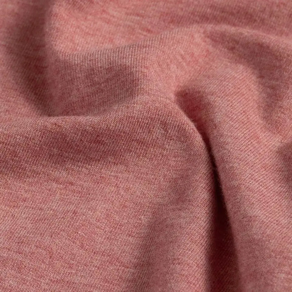 A close-up of draped heathered light red fabric showing its soft texture and fine knit detail.