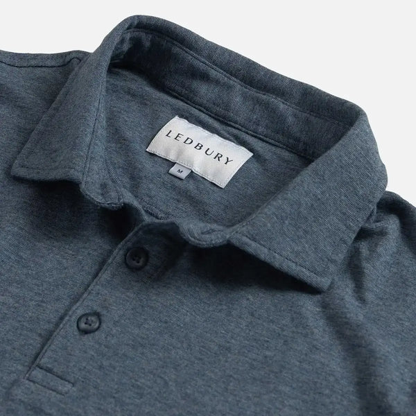 Close-up of a slate blue polo shirt collar with a visible LEDBURY neck label and two dark buttons on a light gray background.