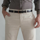 A close-up of a man wearing light khaki chinos with a black leather belt and a dark gray button-down shirt, cropped from the chest down.