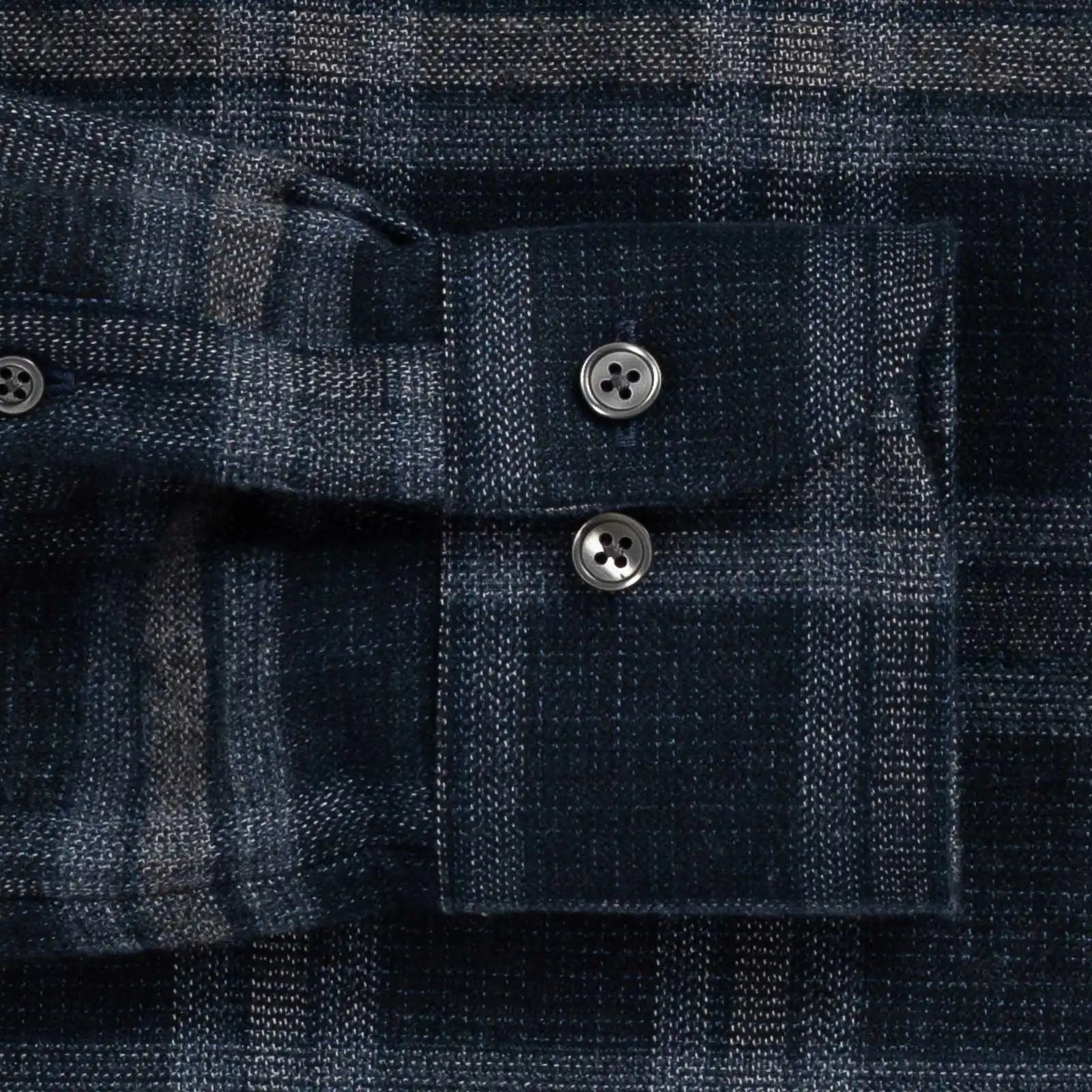Close-up of a dark blue plaid shirt sleeve cuff with buttons