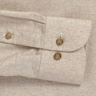 Close-up of a beige textured herringbone shirt with buttons 
