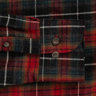 Close-up of a red and black plaid flannel shirt cuff with two buttons and white stripe lines.