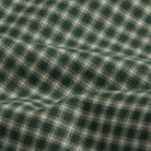 A close-up of a dark green and off-white plaid fabric with a soft, draped texture.