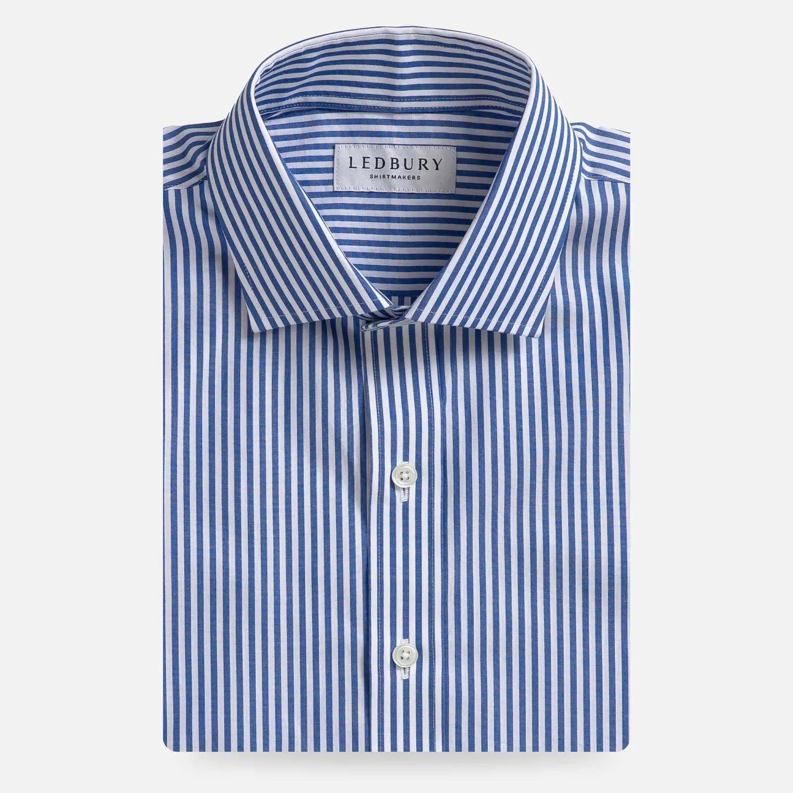 A folded men's dress shirt by Ledbury, featuring a blue and white vertical stripe pattern, a classic collar, and white buttons, presented on a clean light gray background.