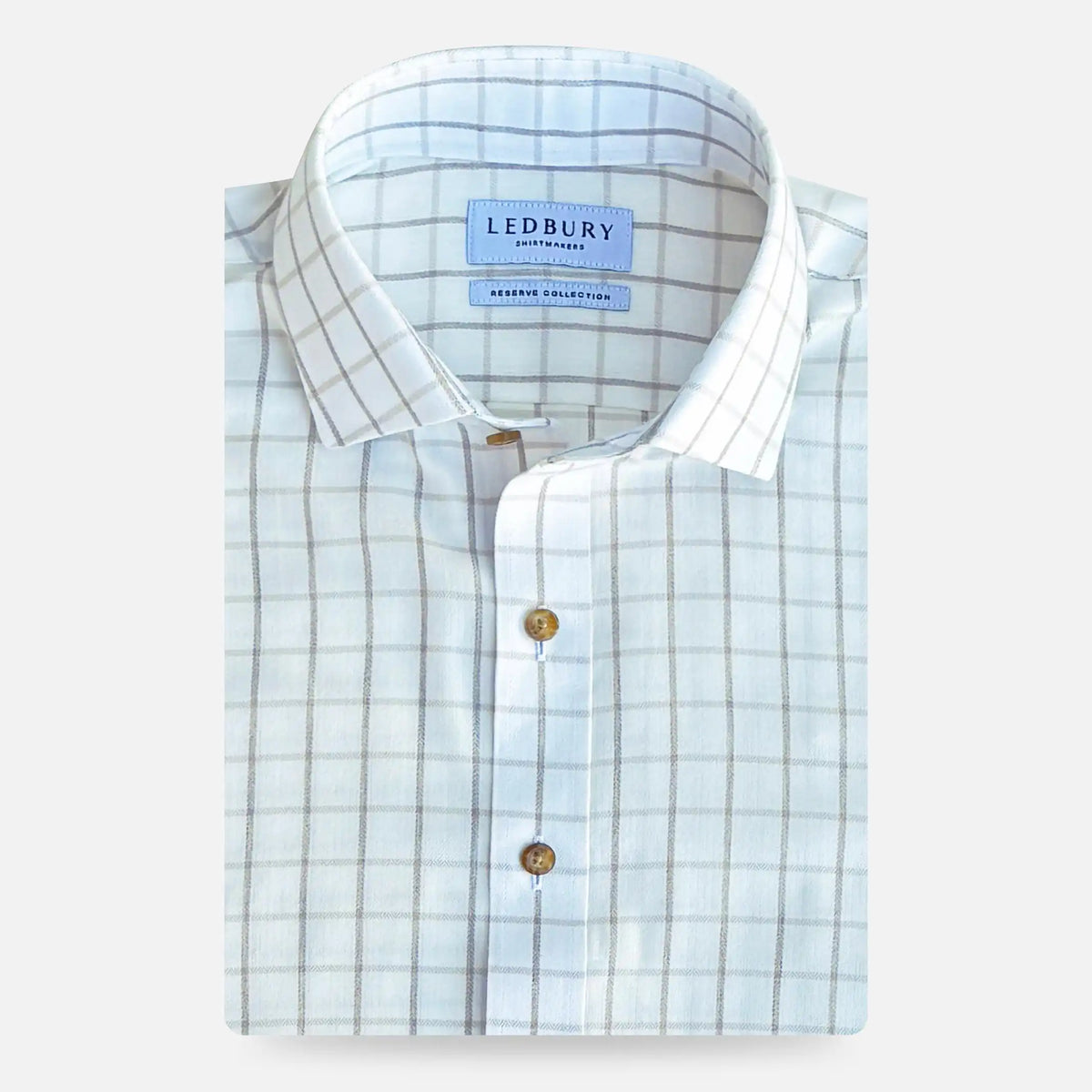 A folded light beige and white checkered dress shirt with brown buttons, featuring a visible LEDBURY brand label on the collar, set against a light gray background.