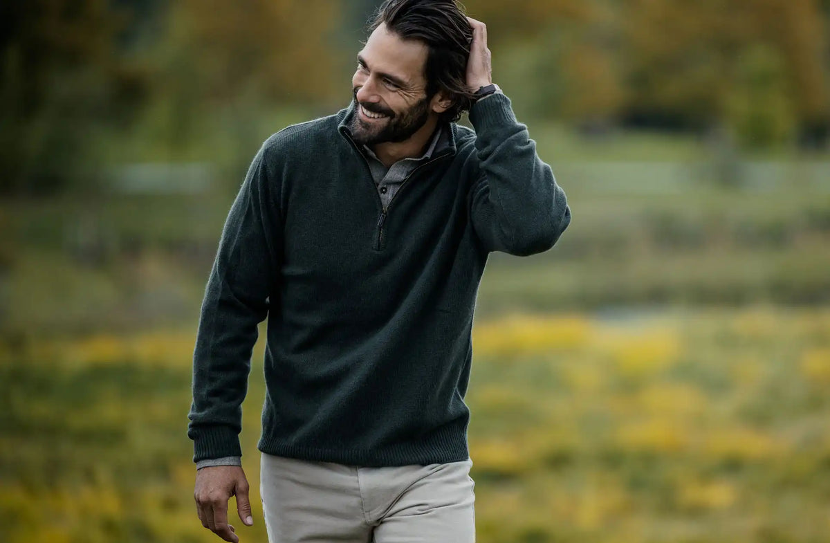 Man in a green sweater standing in a field with blurred background
