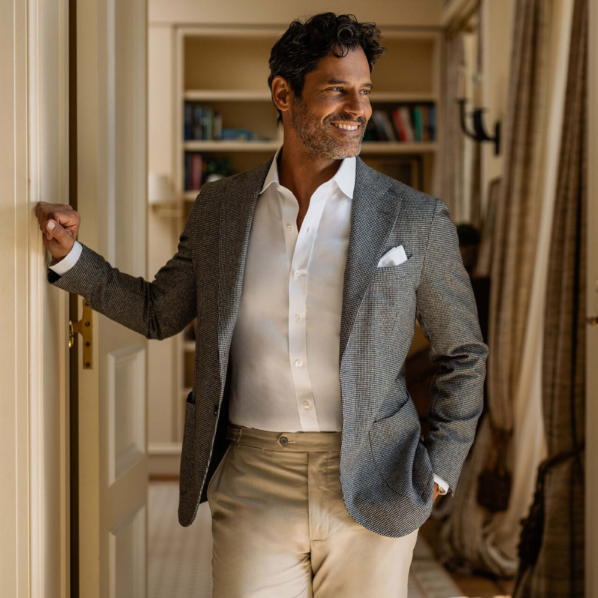 Man in a suit standing in a room with bookshelves in the background