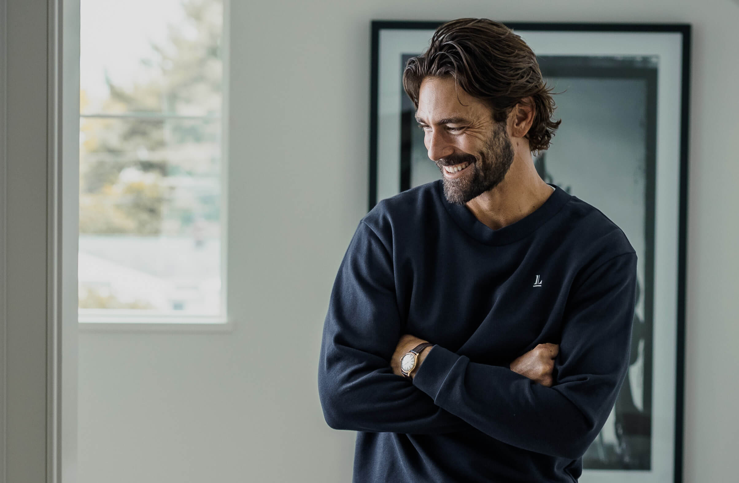 Model wearing the Ledbury pullover sweatshirt, standing with his arms crossed in a doorway