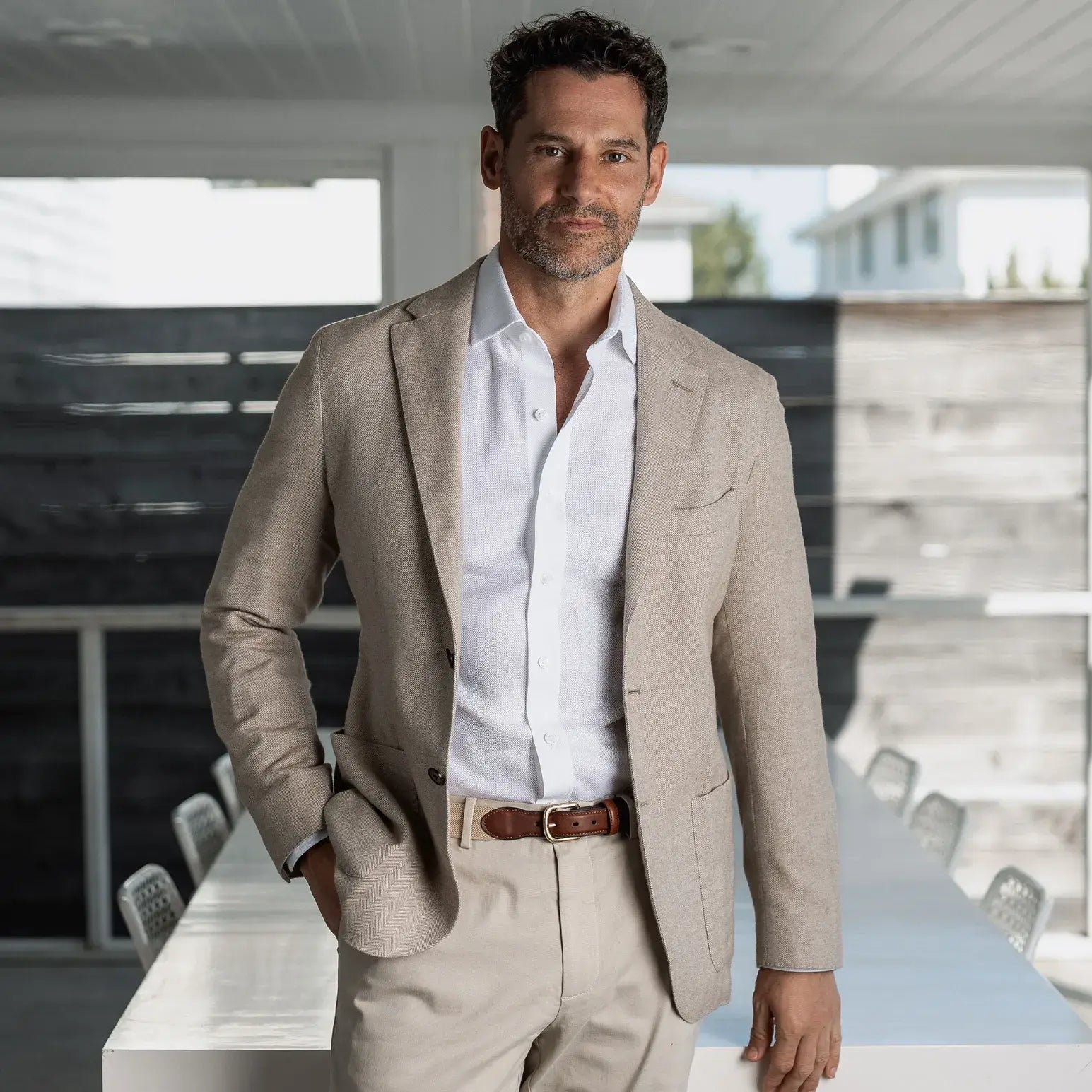 Man in a beige suit and white dress shirt standing outside