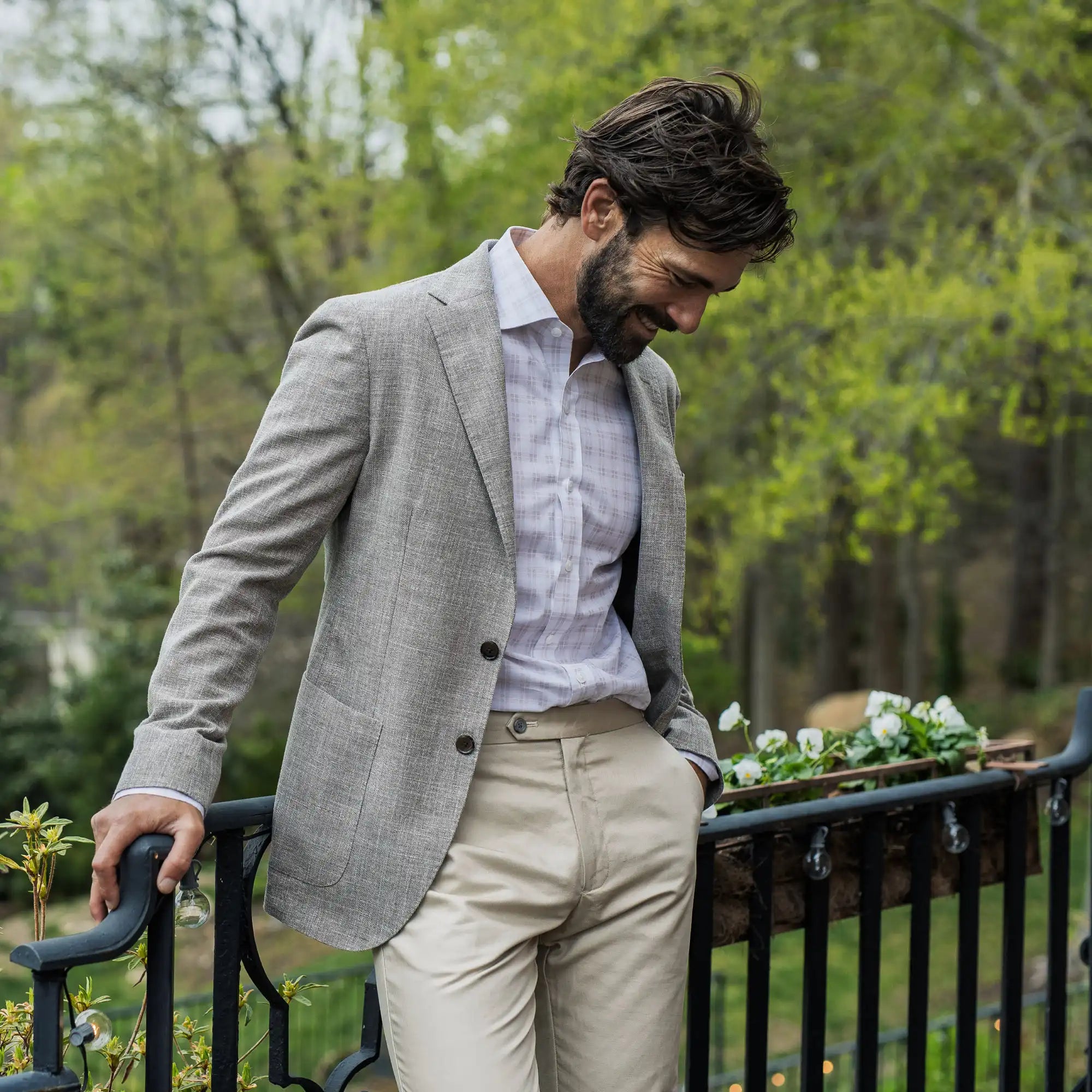 Male model wearing a Ledbury pink and white dress shirt and a tan blazer. He is standing on an outdoor deck. 