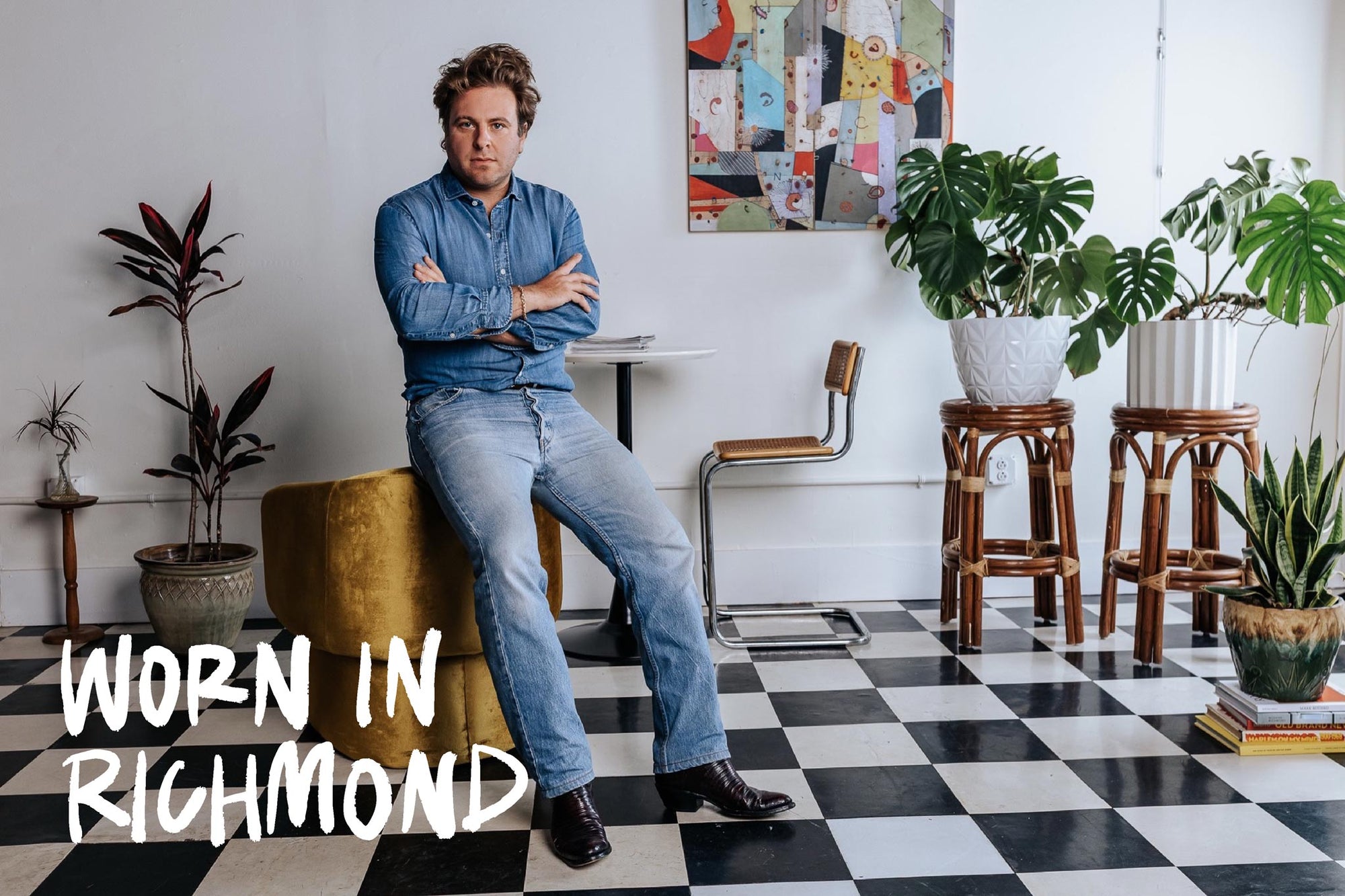 Man sitting on a chair in a room with plants and checkered floor, with 'Worn in Richmond' text.